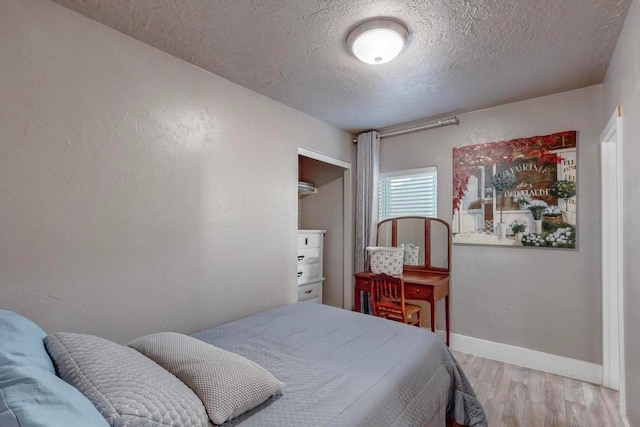 bedroom with a textured ceiling and light hardwood / wood-style flooring