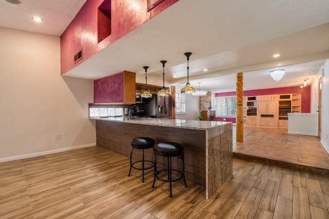 kitchen featuring light hardwood / wood-style flooring, kitchen peninsula, a kitchen breakfast bar, and stainless steel appliances