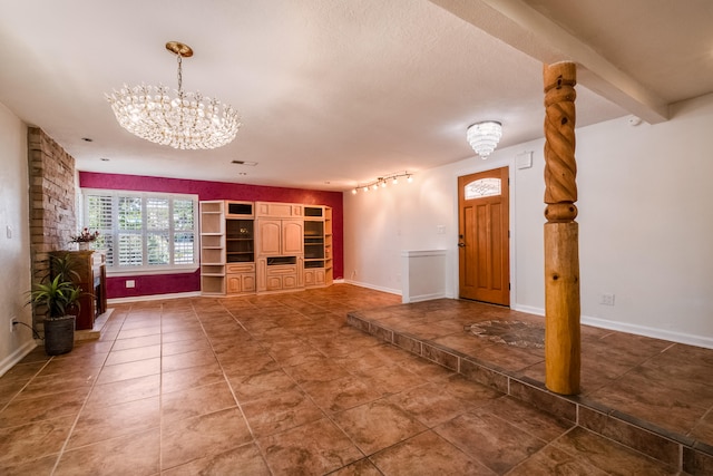 unfurnished living room with track lighting, a notable chandelier, and dark tile patterned flooring