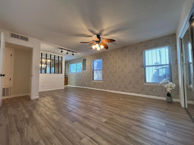 unfurnished room featuring wood-type flooring, ceiling fan, track lighting, and a textured ceiling