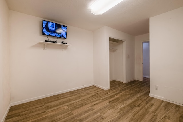 unfurnished bedroom featuring a spacious closet, a closet, and hardwood / wood-style flooring