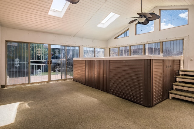 unfurnished sunroom featuring ceiling fan, vaulted ceiling with skylight, wood ceiling, and a healthy amount of sunlight