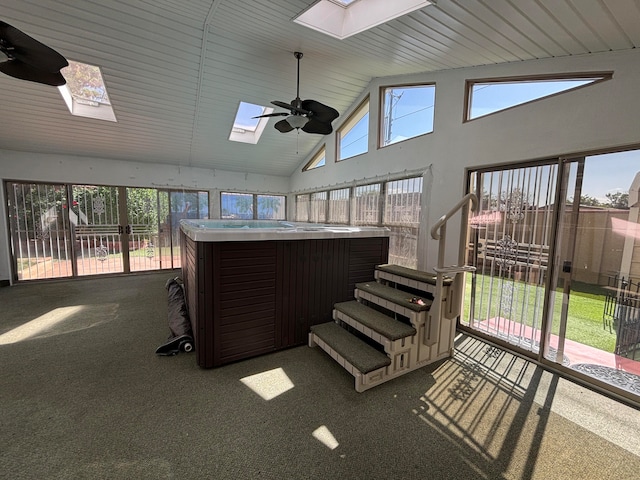 sunroom featuring vaulted ceiling with skylight, a hot tub, and ceiling fan