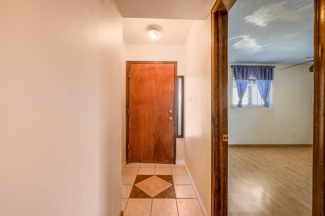 hallway with light wood-type flooring and a textured ceiling