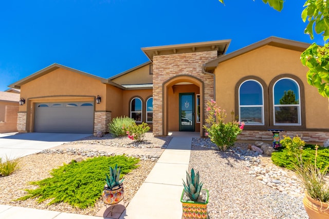 mediterranean / spanish-style home featuring stucco siding, concrete driveway, an attached garage, and stone siding