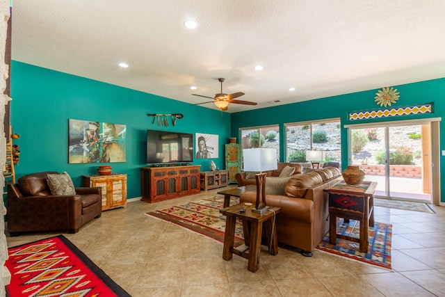 living room with light tile patterned flooring, a textured ceiling, and ceiling fan