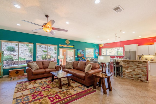 living room featuring visible vents, light tile patterned floors, ceiling fan, and plenty of natural light