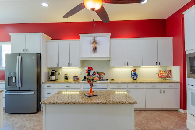 kitchen featuring a kitchen island, white cabinets, stainless steel refrigerator with ice dispenser, a ceiling fan, and light tile patterned flooring