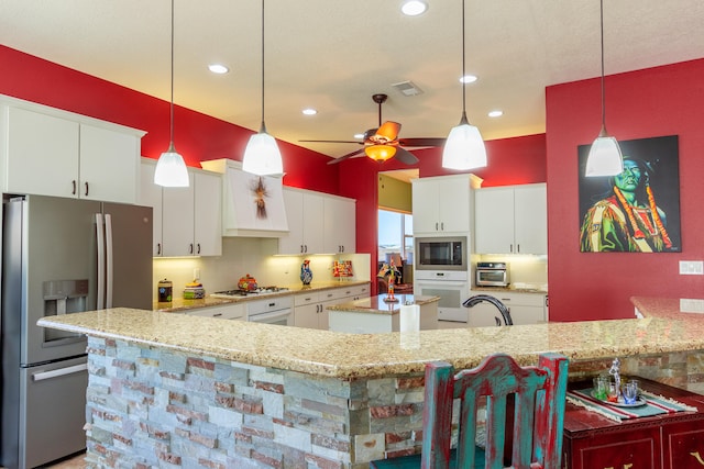 kitchen featuring white cabinets, ceiling fan, stainless steel appliances, and pendant lighting