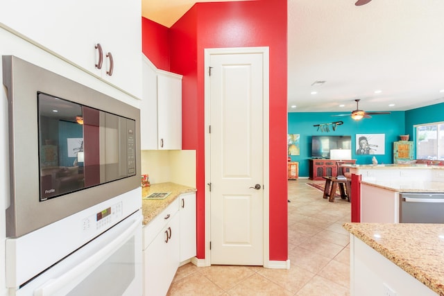 kitchen featuring white oven, ceiling fan, open floor plan, and white cabinets