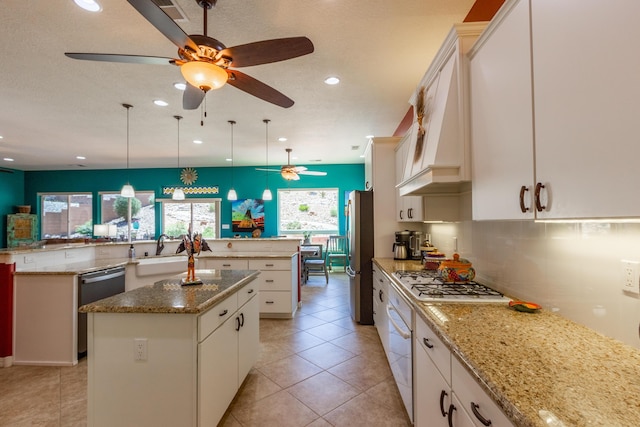 kitchen with gas stovetop, a ceiling fan, white oven, a large island with sink, and freestanding refrigerator