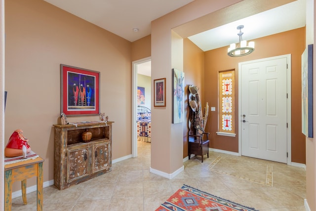 entryway featuring an inviting chandelier, tile patterned flooring, and baseboards