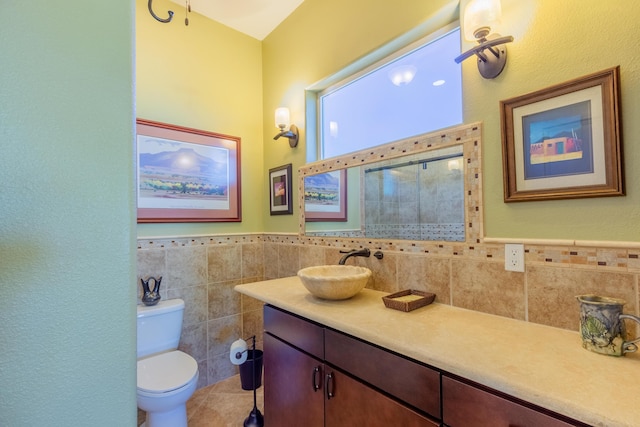 bathroom with tile walls, vanity, tile patterned floors, toilet, and wainscoting