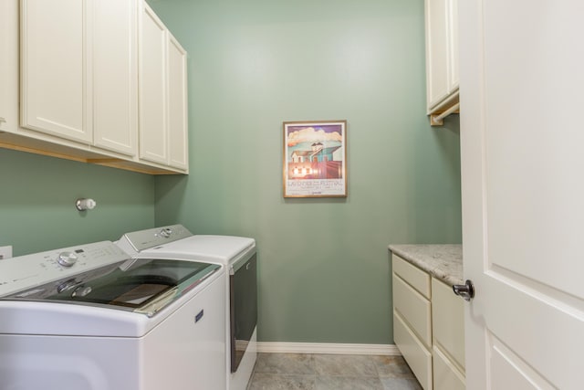 clothes washing area featuring separate washer and dryer, cabinet space, and baseboards