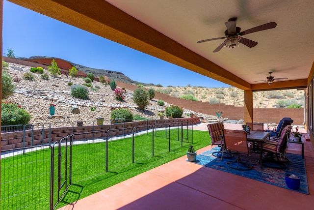 view of patio / terrace with a mountain view, outdoor dining space, ceiling fan, and a fenced backyard