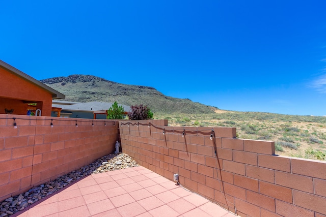 view of patio / terrace with fence and a mountain view