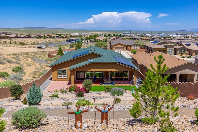 view of front of house featuring a mountain view, solar panels, a fenced backyard, and a patio area
