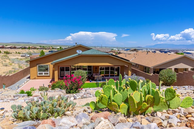 rear view of house with stucco siding, a patio area, a mountain view, and fence private yard