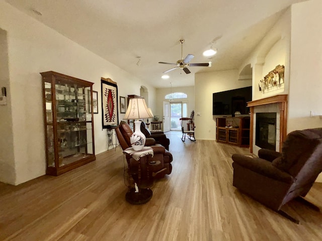 living room featuring a tiled fireplace, hardwood / wood-style floors, and ceiling fan