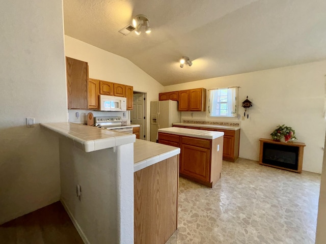 kitchen with white appliances, vaulted ceiling, a textured ceiling, tile countertops, and kitchen peninsula