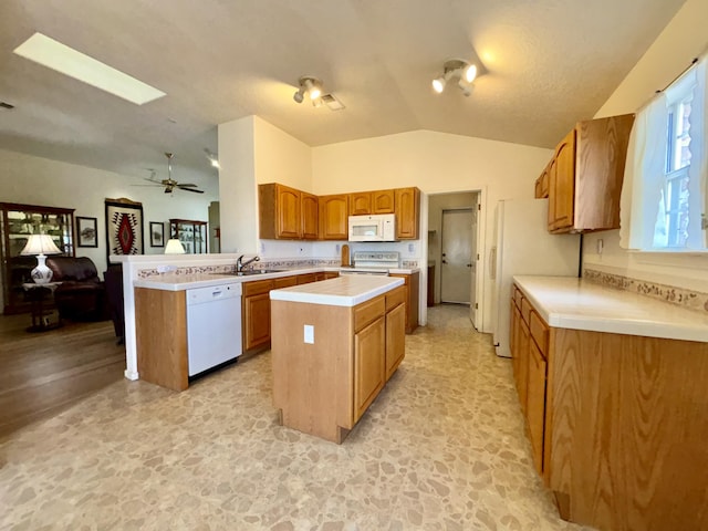 kitchen with vaulted ceiling, a kitchen island, sink, kitchen peninsula, and white appliances