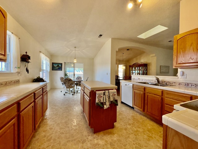 kitchen featuring sink, decorative light fixtures, tile counters, white dishwasher, and a kitchen island