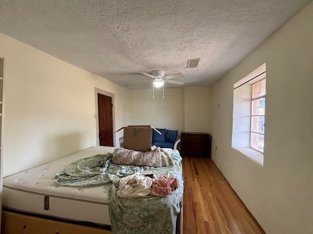 bedroom featuring ceiling fan, light hardwood / wood-style floors, and a textured ceiling