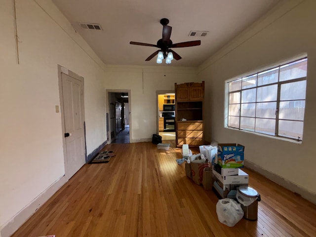 interior space with ornamental molding, ceiling fan, and light hardwood / wood-style floors