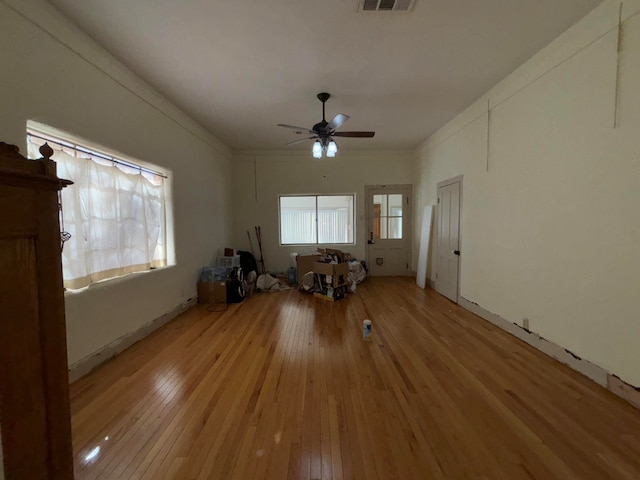 unfurnished living room with crown molding, ceiling fan, and light hardwood / wood-style flooring