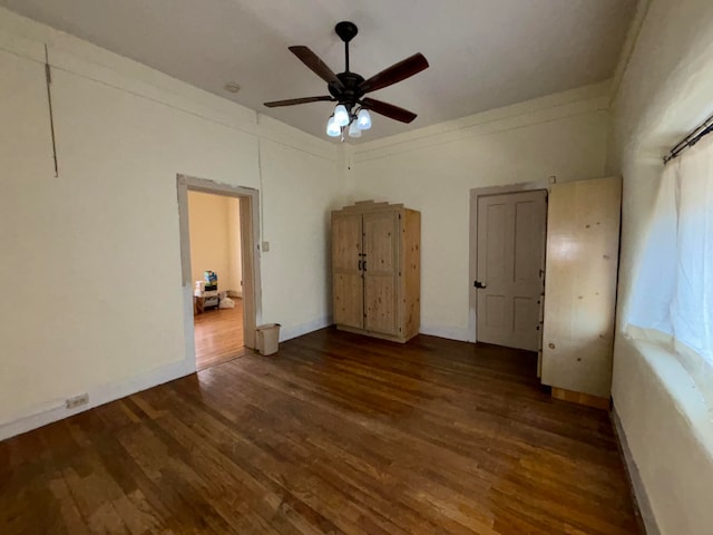 unfurnished bedroom with ceiling fan and dark wood-type flooring