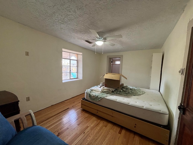 unfurnished bedroom with light hardwood / wood-style flooring, a textured ceiling, and ceiling fan