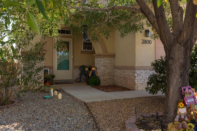 doorway to property featuring stone siding and stucco siding