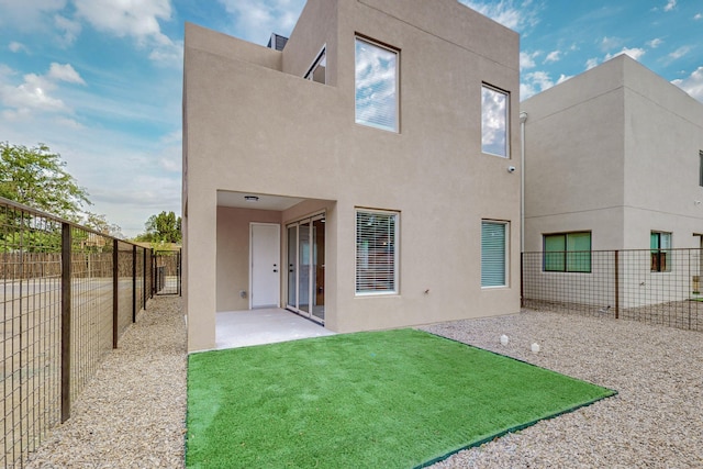 back of property featuring a patio area and a lawn