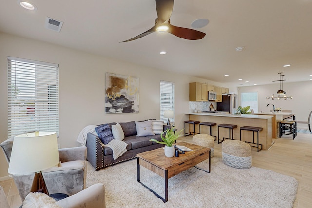 living room with sink, light hardwood / wood-style floors, and ceiling fan