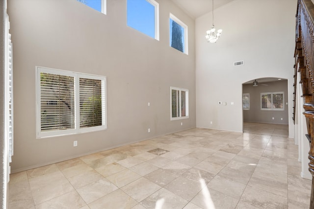 unfurnished living room featuring a towering ceiling and ceiling fan with notable chandelier