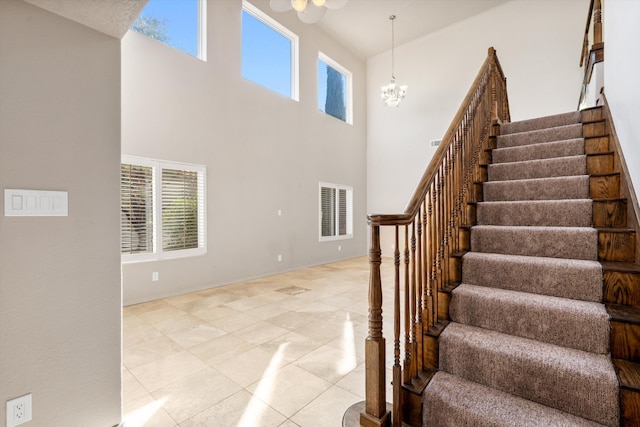 stairway featuring tile patterned floors, a towering ceiling, and an inviting chandelier