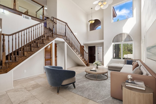 living room with crown molding, ceiling fan, and a high ceiling