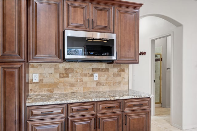 kitchen with decorative backsplash, light stone countertops, and light tile patterned floors