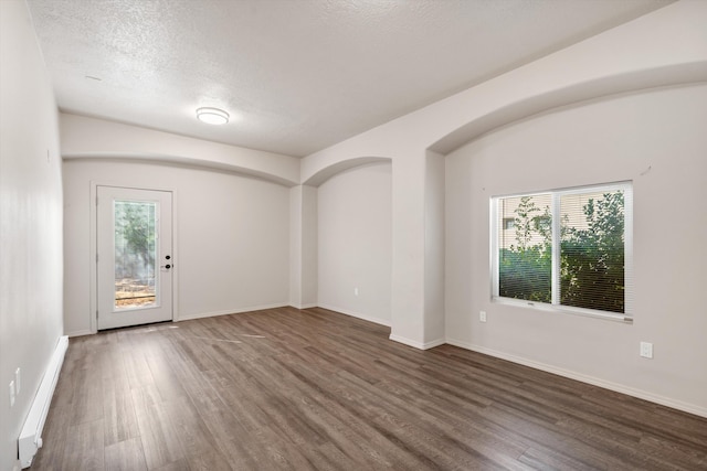 unfurnished room with a textured ceiling and dark hardwood / wood-style floors