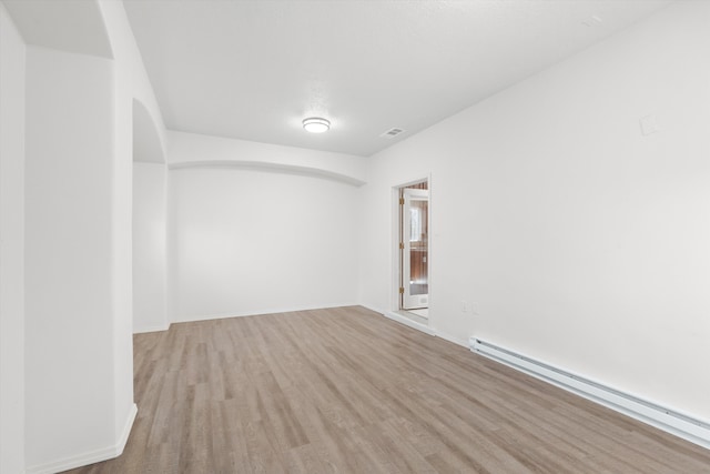 spare room with a baseboard radiator and light hardwood / wood-style flooring