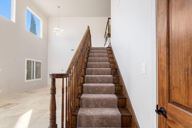 staircase featuring a notable chandelier and a towering ceiling