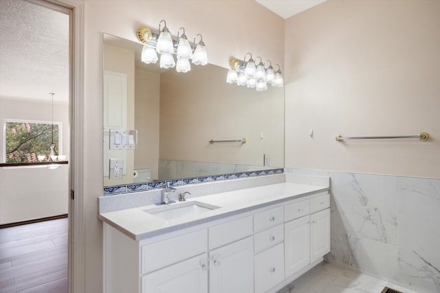 bathroom featuring hardwood / wood-style flooring, vanity, toilet, and tile walls