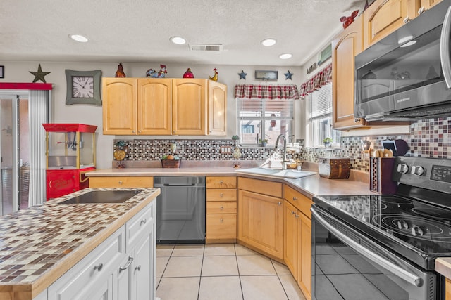 kitchen with a textured ceiling, stainless steel appliances, sink, and backsplash