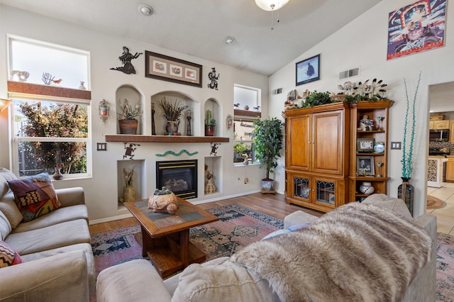 living room with ceiling fan, high vaulted ceiling, and light wood-type flooring