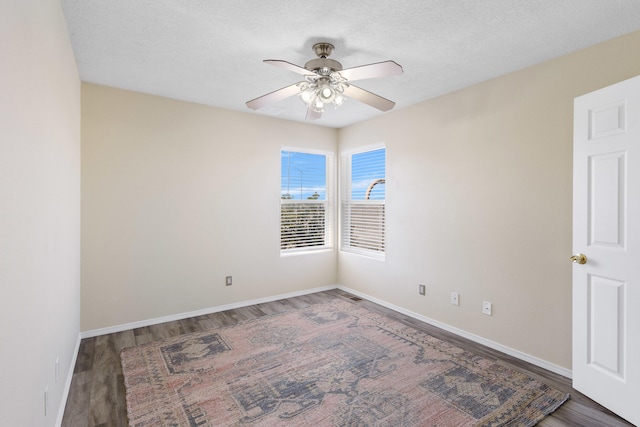 unfurnished room with ceiling fan, a textured ceiling, and dark hardwood / wood-style floors