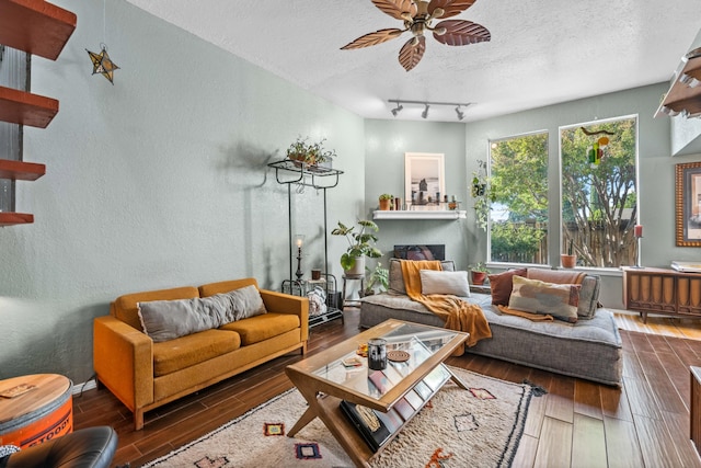 living room featuring dark wood-type flooring, ceiling fan, and a textured ceiling