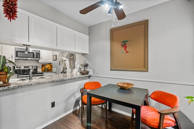 kitchen featuring decorative backsplash, dark hardwood / wood-style flooring, white cabinetry, light stone countertops, and stainless steel appliances