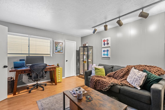 living room featuring a textured ceiling, light wood-type flooring, and rail lighting