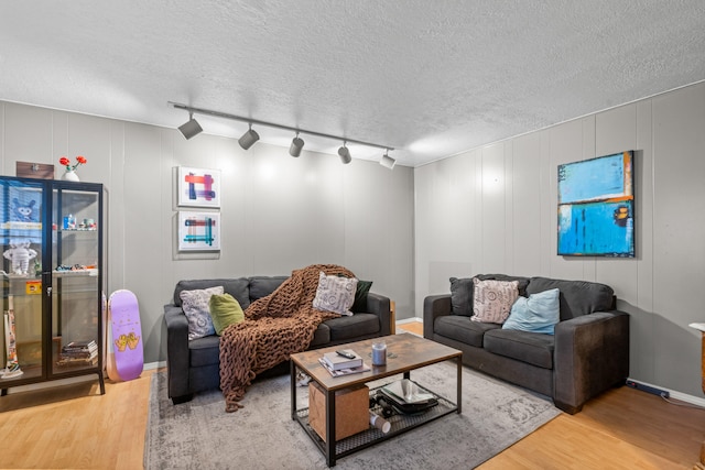 living room featuring rail lighting, a textured ceiling, and hardwood / wood-style floors