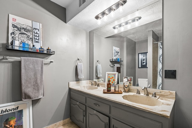 bathroom with toilet, a textured ceiling, vanity, and tile patterned floors